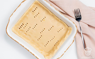 Подготовьте основу для печенья. Большую часть теста раскатайте в пласт. В форму для выпечки выложите раскатанное тесто и поставьте в морозильную камеру на 10 минут. Затем включите духовку на 180 градусов. Достаньте форму из морозилки и проколите в нескольких местах вилкой. Поставьте основу для печенья выпекаться на 15 минут.