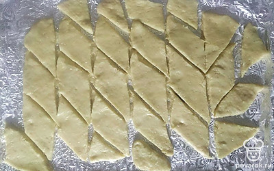 Присыпьте стол мукой и раскатайте скалкой тесто слоем около 5-7 мм. Раскатанное тесто переложите на фольгу или бумагу для выпечки и разрежьте на одинаковые ромбы.