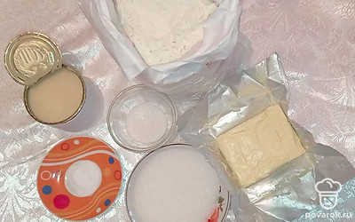 Откройте банку сгущенки, сахар насыпьте в тару, а сливочное масло вытащите из холодильника. Разрыхлитель насыпьте в тарелку. Отмерьте 400 г муки и разместите в пакете.