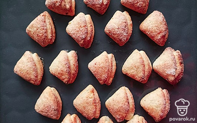 Остуженное тесто раскатайте при помощи скалки или в крайнем случае при помощи рук. Вырежьте из теста кружечки и обмакните их в сахар, далее складывайте наполовину до получения треугольников. Поставьте противень в духовку на 25 минут при температуре 180 градусов.