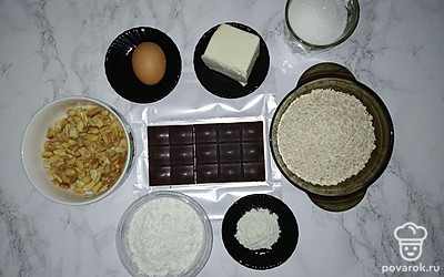 Овсяные хлопья измельчите в блендере, шоколад и орехи измельчите с помощью ножа на маленькие кусочки.