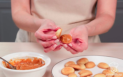 Начините половинки орешков. В каждую половинку выложите начинку из вареной сгущенки и соедините две половинки между собой.