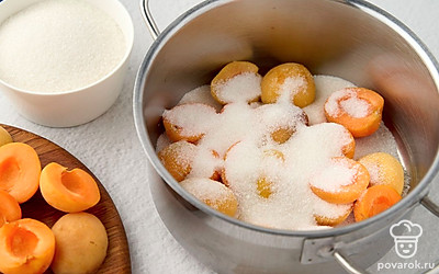 Выложите половину абрикосов в кастрюлю срезом вверх. Посыпьте половиной сахара.