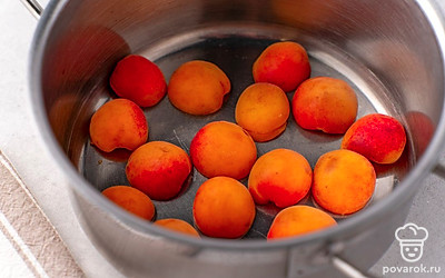 Положите половинки абрикосов в кастрюлю, аккуратно выкладывая их на дно и друг на друга ровными слоями.