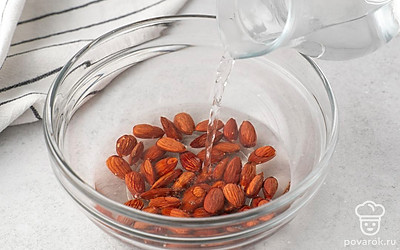 Выложите миндаль в миску, залейте его горячей водой. Дайте орехам постоять 10-15 минут. Слейте воду и снимите с миндаля коричневую шелуху.