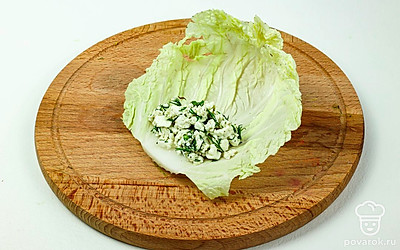 Возьмите 1 лист пекинской капусты и выложите на его край 2 ст. л. творожной начинки.