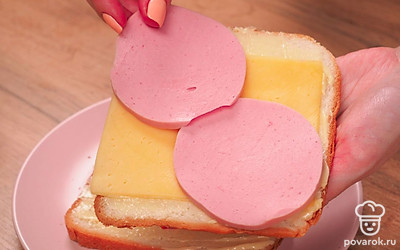 Соберите сэндвичи. Положите на смазанные маслом ломтики хлеба тонкие кусочки сыра (можно в 2 слоя), затем – кусочки колбасы (можно по 2 штуки на 1 сэндвич), поверх колбасы – ещё по слою сыра. Накройте сэндвич ломтиками хлеба масляной стороной к начинке.