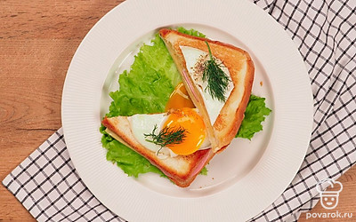 Можно подать каждый сэндвич на отдельной тарелочке, положив под хлеб лист салата, а на глазунью – веточки укропа. Посолить поперчить по вкусу и проколоть желток