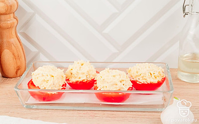 Разрежьте помидоры пополам и выложите их в форму для запекания. На каждую половинку помидора выложите начинку и отправьте запекаться в духовку, предварительно разогретую до 180 ℃ на 5-7 минут. Готовые помидоры подавайте горячими к столу.