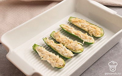 Кабачки разрежьте пополам, выньте столовой ложкой середину и нафаршируйте полученной начинкой. Выложите цуккини в форму для запекания и готовьте их в разогретой до 180 градусов духовке в течение 15-20 минут.