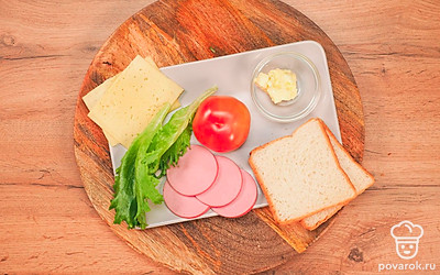 Расположите удобно все продукты. Нарежьте на кусочки толщиной 2 мм колбасу, сыр. Томат нарежьте кружочками толщиной 3-5 мм. Листья салата промойте и просушите.