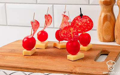 Вонзите кончик шпажки в сыр. Если все сделано правильно, сырная основа придаст канапе устойчивость. Повторите то же самое с оставшимися продуктами и поставьте готовые канапе на плоскую тарелку или блюдо.