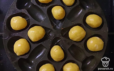 Разогрейте сковороду с двух сторон и смажьте ее поверхность растительным маслом. Сформируйте из теста небольшие шарики и уложите их в углубления формы, прижмите верхней частью формы.