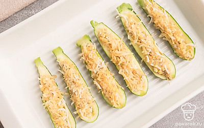 Кабачки разрежьте пополам, выньте столовой ложкой середину и нафаршируйте полученной начинкой. Выложите в форму для запекания цуккини и готовьте их в разогретой до 180 градусов духовке в течение 15-20 минут.