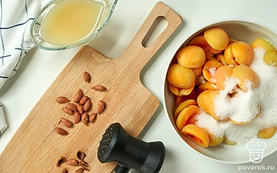 Подготовьте абрикосы. Каждый абрикос разрежьте пополам, извлеките косточку. Из косточек достаньте ядрышки при помощи молотка. Половинки абрикосов засыпьте сахаром, перемешайте и оставьте на 4 часа при комнатной температуре.