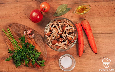 Подготовьте банки и крышки для хранения икры. Вымойте их с жидкостью для мытья посуды. Хорошо промойте и высушите. Простерелизуйте 10 минут в духовке при температуре 120 ˚C. Ставьте банки в холодную духовку. Крышки стерелизуются отдельно. Их нужно проварить в кипящей воде 10-15 минут. Положите банки и крышки на чистое полотенце остывать. Очистите опята от земли и листвы. Хорошо промойте проточной водой, но не замачивайте, так как опята очень хрупкие. Вымойте лук и очистите его от шелухи. Нарежьте на небольшие кусочки. Приготовьте мясорубку. Очистите чеснок. Вымойте морковь. Очистите от кожуры и натрите на мелкой терке. Вымойте петрушку. Отрежьте ножки, чтобы остались только листья.