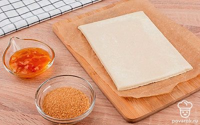 Слоеное тесто разморозьте. Желток отделите от белка. Разогрейте духовку до 180 °С.