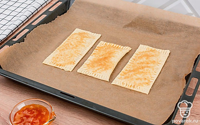 Противень выстелите пергаментом. Выложите слойки. Выпекайте в духовке 15-20 минут при 180⁰С, пока они не станут золотистыми.