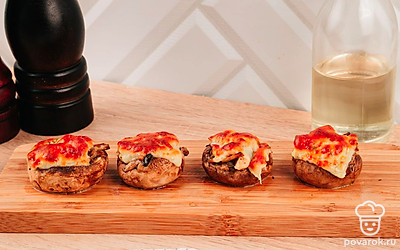 Грибы достаньте из духовки, внутрь шляпок выложите готовую начинку. Затем сыр нарежьте на ломтики, соразмерных диаметру шляпок. Накройте каждую шляпку кусочком сыра и отправьте в духовку на 10 минут при 180 °С.