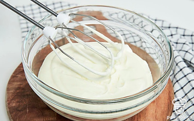 Приготовьте домашние сливки. Достаньте молоко с маслом из холодильника, перелейте его в удобную емкость и начните взбивать миксером на самом медленном режиме. По мере того, как сливки начнут густеть, постепенно увеличивайте скорость, но не доводите до максимальной. Готовые взбитые сливки должны удерживаться на пиках и не опадать при движении.