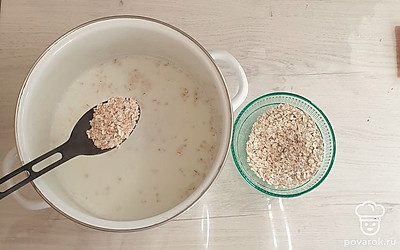 К молоку всыпьте овсянку. Варите на медленном огне, периодически помешивая, 5-7 минут.