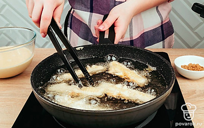 В глубокую сковороду налейте большое количество масла. Выложите крабовые палочки.