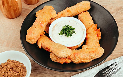 Обжаренные в кляре крабовые палочки выложите по краям красивой плоской тарелки, а в середину поставьте розетку с соусом и украсьте зеленью.