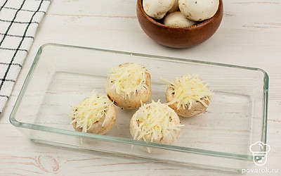 Сверху посыпьте шампиньоны тертым сыром, отправьте в духовку и запекайте в течение 15 минут при 180 ℃.