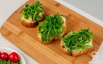 Сверху на авокадо выложите руколу.