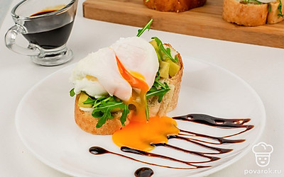 Готовые брускетты выложите на тарелку и сбрызните крем-бальзамиком. Надрежьте яйцо пашот, чтобы жидкий желток придал блюду эффектности.