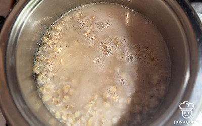 Когда овсянка начнет бурлить, влейте молоко. Так как овсянка без сахара, важно использовать вкусное молоко, которое не испортит вкус каши. Я использую молоко 2,5% жирности. Перемешайте, мощность плиты поставьте на минимум и постоянно помешивайте кашу.