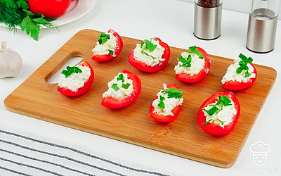 Соберите закуску: наполните начинкой помидорные дольки. Выложите закуску на листья салата, сверху присыпьте зеленью.