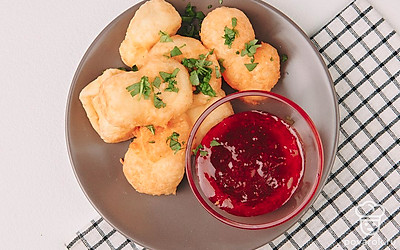 Подайте сырные шарики с кисло-сладким ягодным соусом. Для него подойдут любые замороженые ягоды (брусника, клюква). В небольшую кастрюлю добавьте ягоды, виноградный сок и сахар, поварите 10 минут. Соус готов.