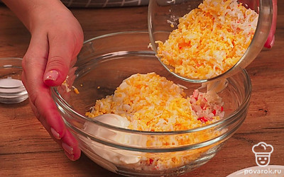 Приступите к подготовке основы для шариков. Добавьте к нарезанным крабовым палочкам пропущенный через пресс чеснок, добавьте плавленый сыр, майонез и яйца. Тщательно перемешайте продукты, приправьте солью и перцем.