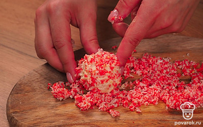 Переходите к завершающему этапу приготовления закуски. Из полученной массы сформируйте шарики, обваляйте каждый в стружке из красной части крабовых палочек.