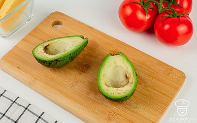 Авокадо разрежьте пополам и удалите косточку с помощью ножа или ложки.