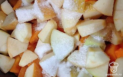 На дно кастрюли налейте растительное масло, выложите половину нарезанной тыквы и яблок, добавьте 2 ложки сахара.