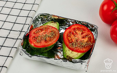 Сверху на авокадо выложите по ломтику помидора. Посолите, поперчите помидоры и посыпьте прованскими травами.