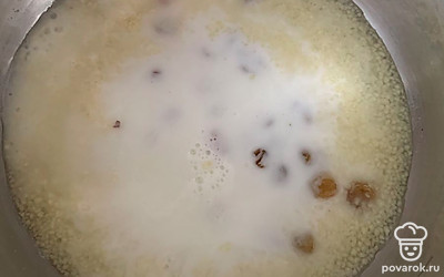 Добавьте распаренный изюм, влейте молоко, доведите до готовности.