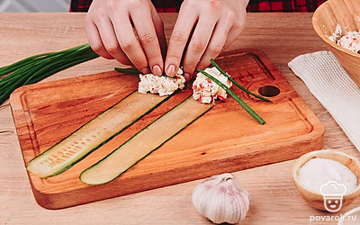 Сверните рулетики. На каждую пластинку из огурца выложите 1 ч. л. крабовой начинки и сверните в рулетик. В середину можно положить перышко зеленого лука.