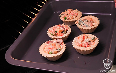 Выставьте тарталетки с начинкой на противень и отправьте в духовку на 15 минут. Запейкате при температуре 170 °С.