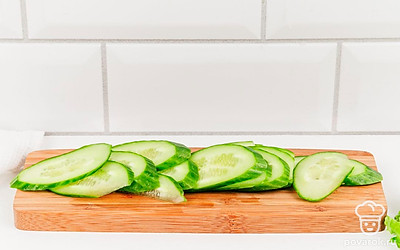 Тем временем огурцы нарежьте тонкими кружочками. Лосось нарежьте тонкими ломтиками.