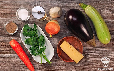 Лук и морковь почистите и измельчите. Баклажан и кабачок помойте, очистите от кожуры и натрите на средней терке. Петрушку промойте под проточной водой, стряхните лишнюю жидкость и мелко нарубите. С чеснока уберите шелуху и пропустите его через пресс. У шампиньонов удалите ножку. Измельчите ее. Кусковой сыр натрите на мелкой терке.