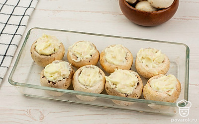 Положите начинку в шляпки грибов и поместите их в форму для выпечки.