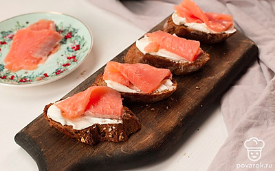 Намажьте багет творожным сыром и выложите ломтики семги.