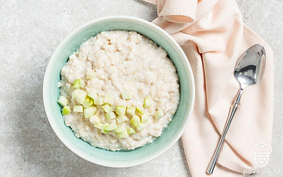 Разложите готовую ячневую кашу по тарелкам. Яблоко нарежьте кубиками или тонкими дольками, а затем выложите поверх блюда в качестве украшения. 