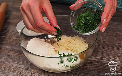 Приготовьте тесто. В глубокой миске смешайте яйца, сметану, всыпьте сыр, муку, соль и перец, а также рубленую зелень. Все тщательно перемешайте.