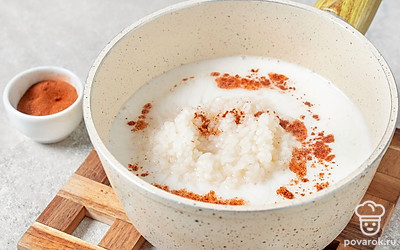 Добавьте молоко в кашу, всыпьте корицу, перемешайте и варите примерно 15 минут до готовности.