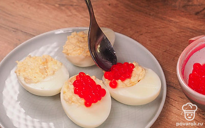 Нафаршируйте яйца. Выложите приготовленную начинку в белковые половинки и украсьте красной икрой.