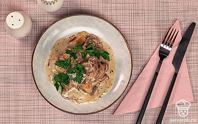 Выложите шампиньоны в сливочном соусе в глубокую тарелку и украсьте веточкой петрушки.